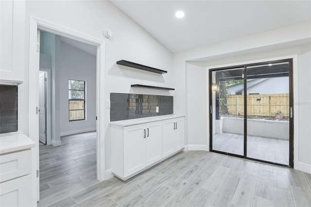 kitchen featuring open shelves, light wood-type flooring, light stone countertops, and white cabinets