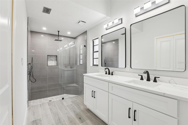 bathroom featuring double vanity, a stall shower, visible vents, and a sink