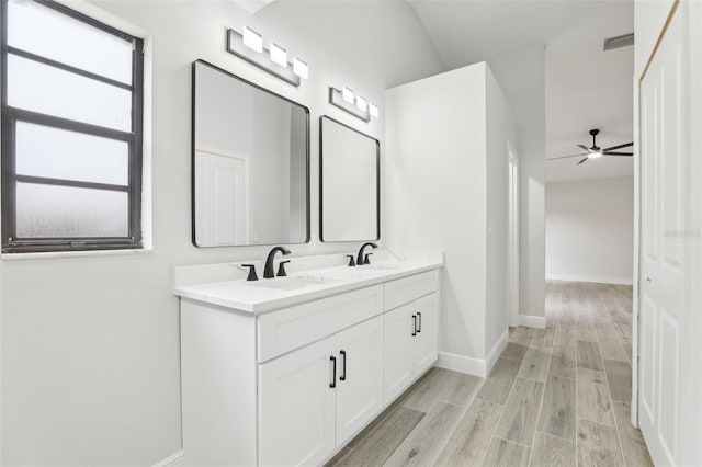 bathroom featuring double vanity, baseboards, visible vents, wood finished floors, and a sink