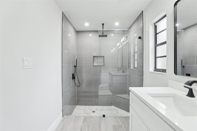 full bath featuring tiled shower and vanity