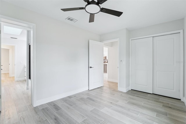 unfurnished bedroom featuring a closet, visible vents, a ceiling fan, light wood-type flooring, and baseboards