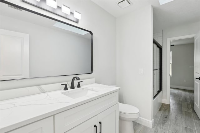 full bath featuring toilet, wood finished floors, vanity, visible vents, and combined bath / shower with glass door