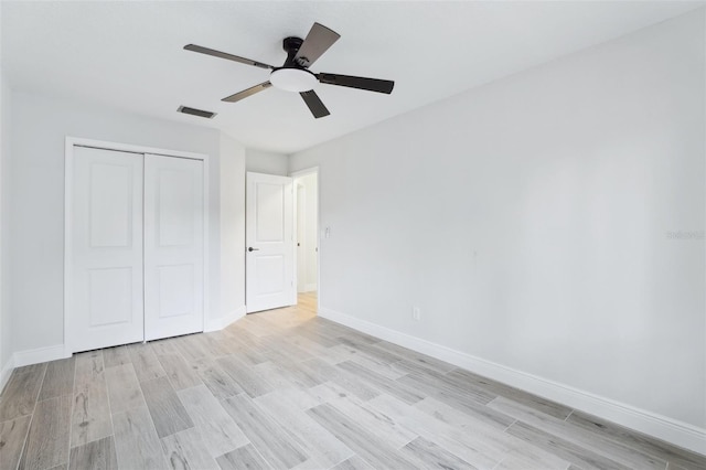 unfurnished bedroom with light wood-type flooring, a closet, visible vents, and baseboards