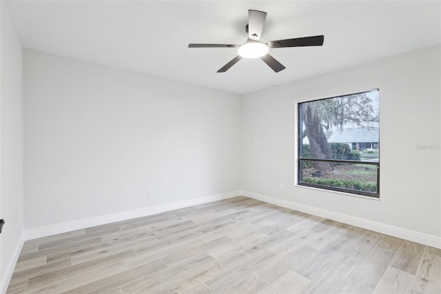 spare room with ceiling fan, light wood finished floors, and baseboards