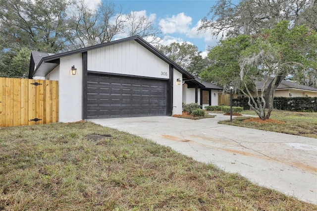 view of front of home featuring concrete driveway, a front lawn, an attached garage, and fence