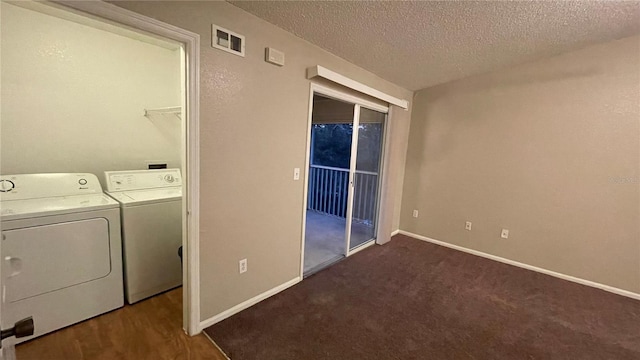 clothes washing area featuring dark carpet, washing machine and dryer, and a textured ceiling