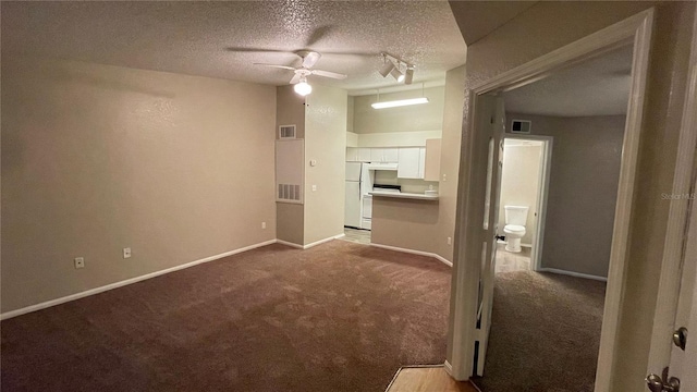 interior space with a ceiling fan, visible vents, a textured ceiling, and carpet flooring