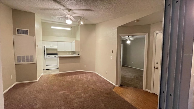 kitchen featuring white cabinetry, range, light colored carpet, and ceiling fan