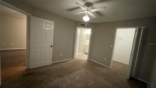 unfurnished bedroom with a walk in closet, carpet, and a textured ceiling