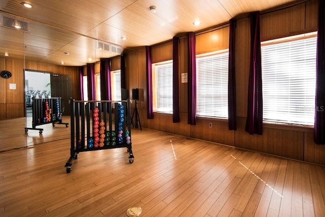 exercise area featuring wood ceiling, plenty of natural light, wooden walls, and light wood-type flooring