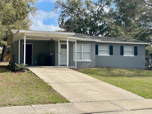 single story home featuring a front lawn, an attached carport, concrete block siding, and concrete driveway