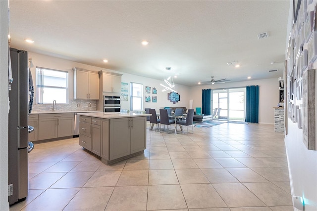 kitchen with a healthy amount of sunlight, appliances with stainless steel finishes, a kitchen island, and backsplash