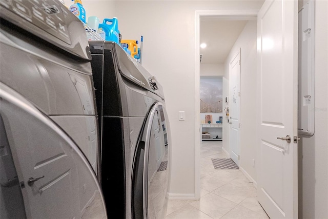 clothes washing area featuring light tile patterned floors and washer and clothes dryer