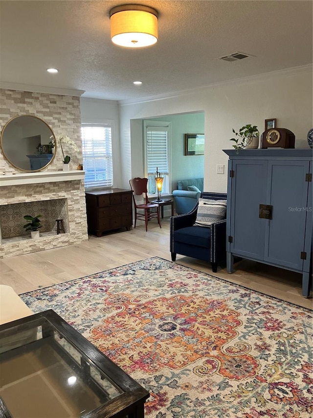 1611 Chestnut Ave, Winter Park, FL 32789 - living room featuring crown molding, light wood-type flooring, a textured ceiling, and a stone fireplace