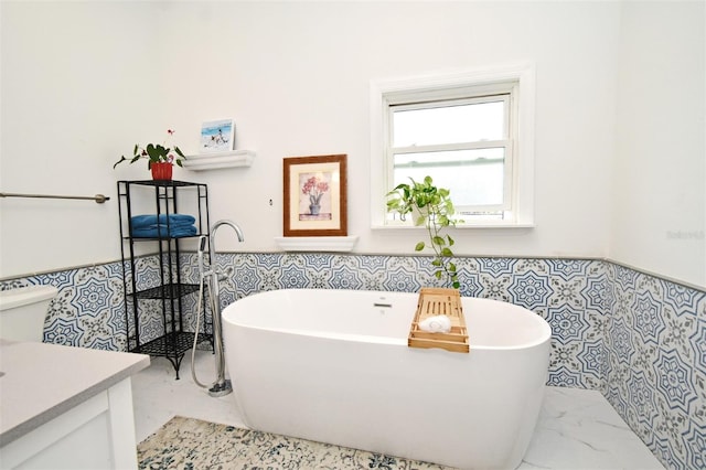 1611 Chestnut Ave, Winter Park, FL 32789 - bathroom featuring marble look tiles, a freestanding bath, vanity, and wainscoting