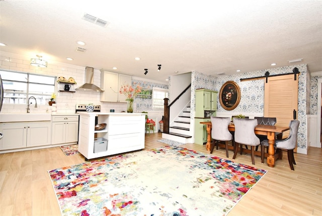 1611 Chestnut Ave, Winter Park, FL 32789 - kitchen featuring wall chimney range hood, a barn door, open shelves, wallpapered walls, and a sink