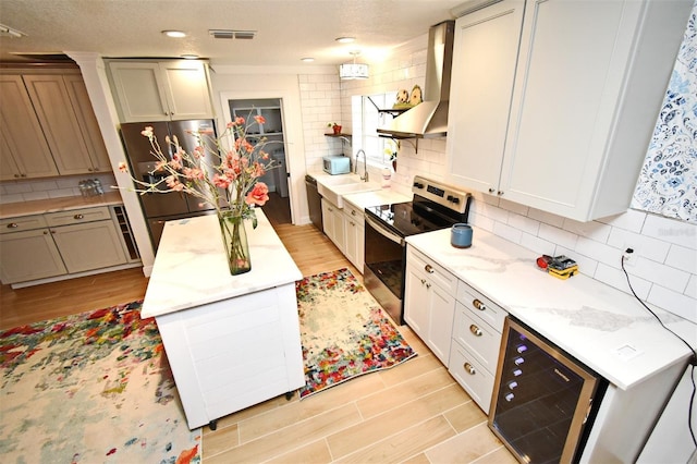 1611 Chestnut Ave, Winter Park, FL 32789 - kitchen with appliances with stainless steel finishes, wall chimney exhaust hood, beverage cooler, and light wood-type flooring