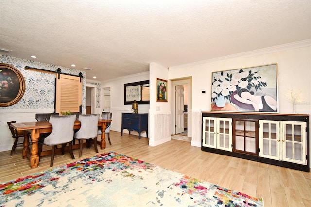 1611 Chestnut Ave, Winter Park, FL 32789 - dining room featuring a barn door, a wainscoted wall, wood finished floors, crown molding, and a textured ceiling
