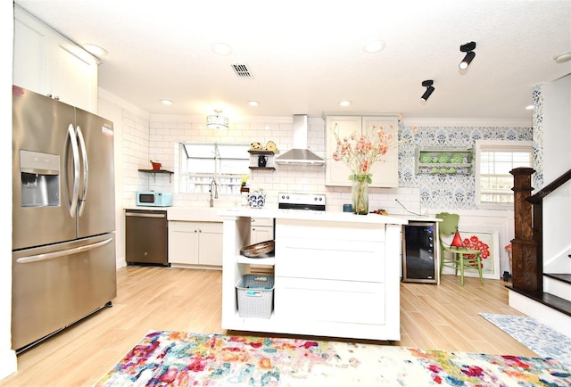 1611 Chestnut Ave, Winter Park, FL 32789 - kitchen with appliances with stainless steel finishes, wine cooler, wall chimney range hood, ornamental molding, and light wood-style floors