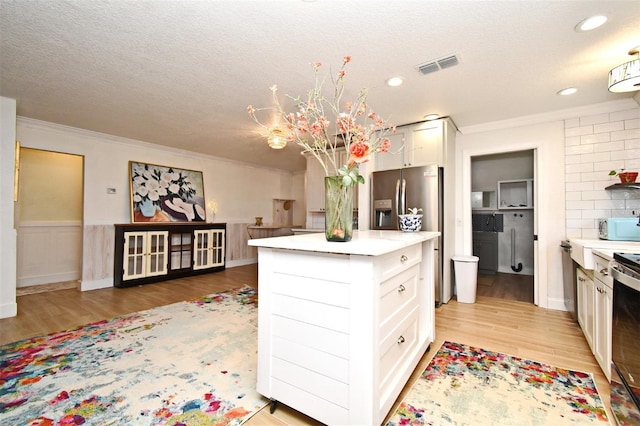 1611 Chestnut Ave, Winter Park, FL 32789 - kitchen featuring crown molding, white microwave, light countertops, light wood-style floors, and white cabinetry