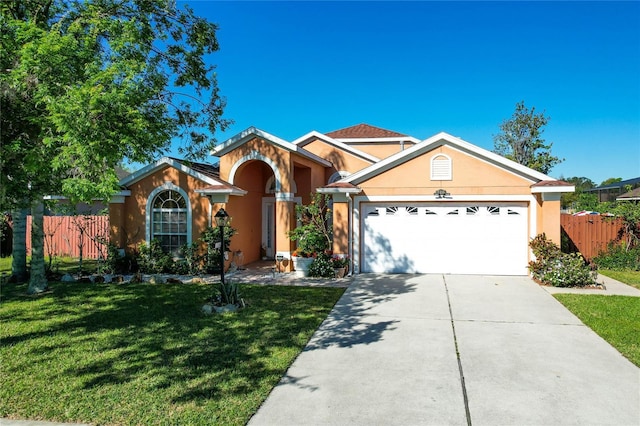 view of front facade with stucco siding, concrete driveway, a front yard, and fence