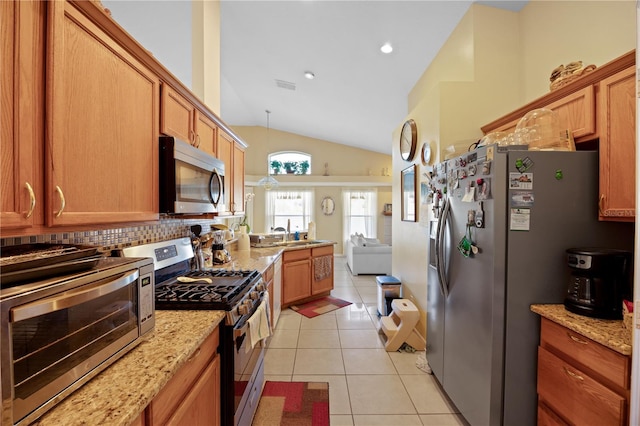 kitchen with open floor plan, lofted ceiling, light tile patterned floors, appliances with stainless steel finishes, and a sink