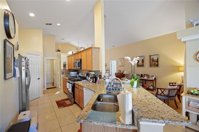 kitchen with a sink, stainless steel appliances, a peninsula, light tile patterned floors, and lofted ceiling