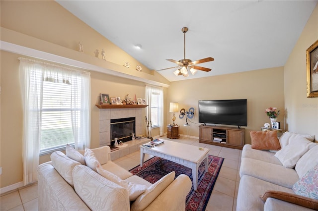 tiled living area featuring baseboards, lofted ceiling, a ceiling fan, and a tiled fireplace