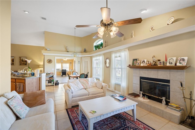 living area featuring a wealth of natural light, visible vents, a fireplace, and a ceiling fan