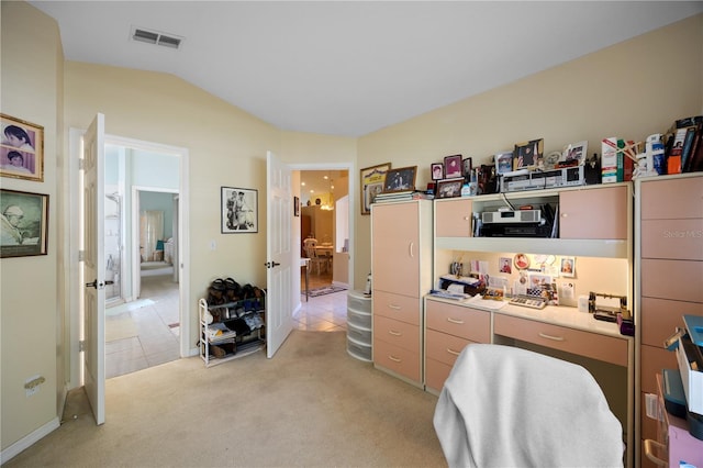 office space with visible vents, lofted ceiling, light colored carpet, and built in study area