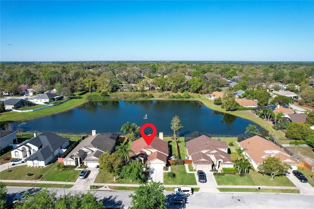 drone / aerial view with a residential view, a wooded view, and a water view