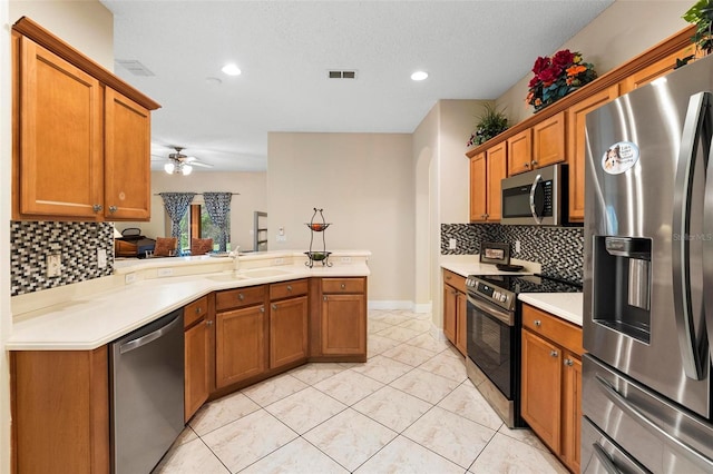 kitchen with visible vents, brown cabinets, stainless steel appliances, light countertops, and a sink