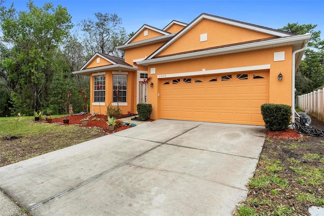 view of front facade featuring a garage, driveway, fence, and stucco siding