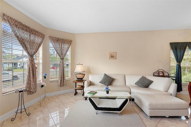 living area with a healthy amount of sunlight, a textured ceiling, and baseboards