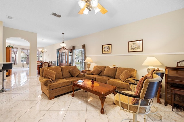 living area with arched walkways, visible vents, and ceiling fan with notable chandelier