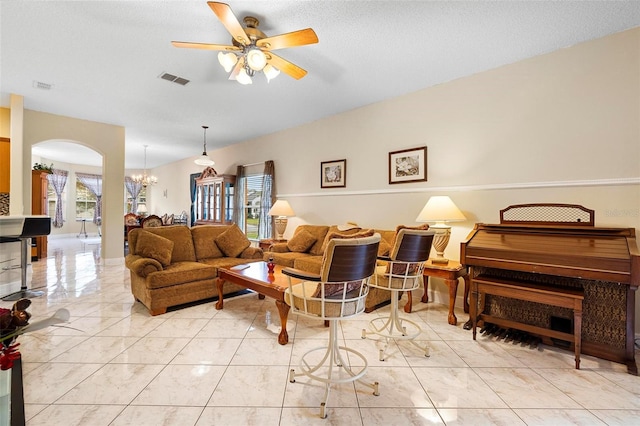 living room with ceiling fan with notable chandelier, a textured ceiling, arched walkways, and visible vents