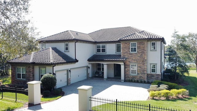 view of front of home featuring an attached garage, a tiled roof, a fenced front yard, and concrete driveway