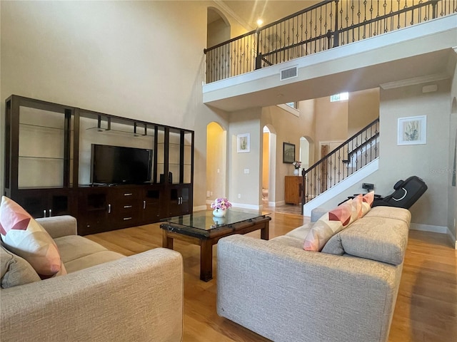 living room with baseboards, arched walkways, stairway, wood finished floors, and a high ceiling