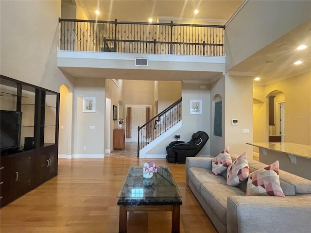 living area featuring ornamental molding, stairway, wood finished floors, and a towering ceiling