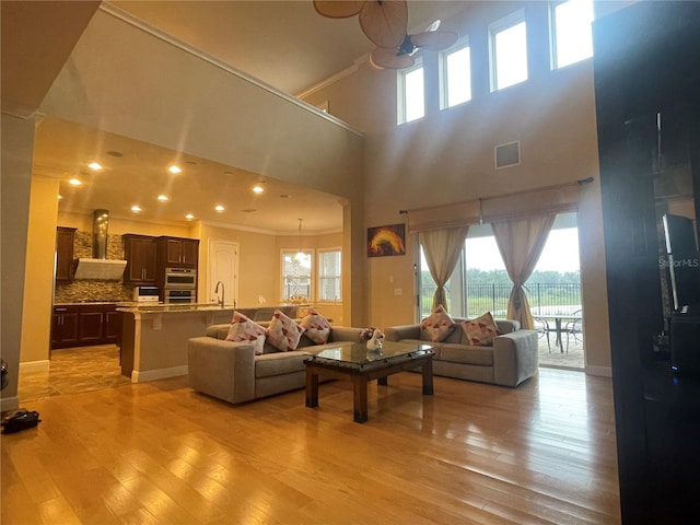 living room featuring recessed lighting, visible vents, baseboards, light wood finished floors, and crown molding