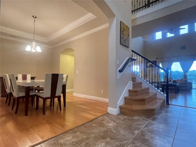 dining space with arched walkways, visible vents, ornamental molding, stairway, and an inviting chandelier