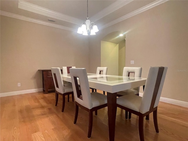 dining space featuring baseboards, light wood finished floors, a raised ceiling, and a notable chandelier