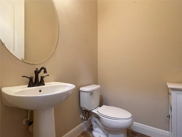 half bathroom featuring baseboards and toilet