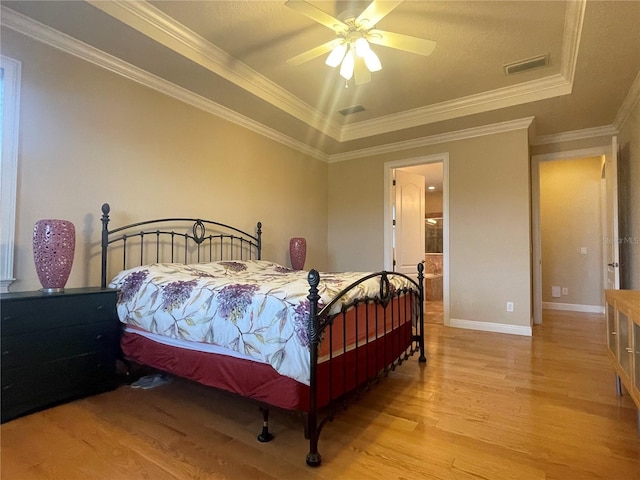 bedroom featuring baseboards, visible vents, a raised ceiling, crown molding, and light wood-type flooring