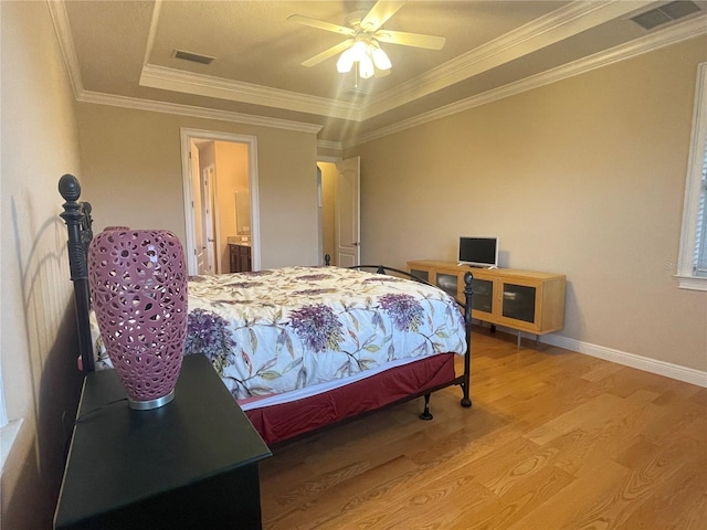 bedroom featuring ornamental molding, a raised ceiling, visible vents, and wood finished floors