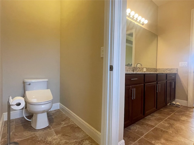 bathroom with toilet, baseboards, and vanity