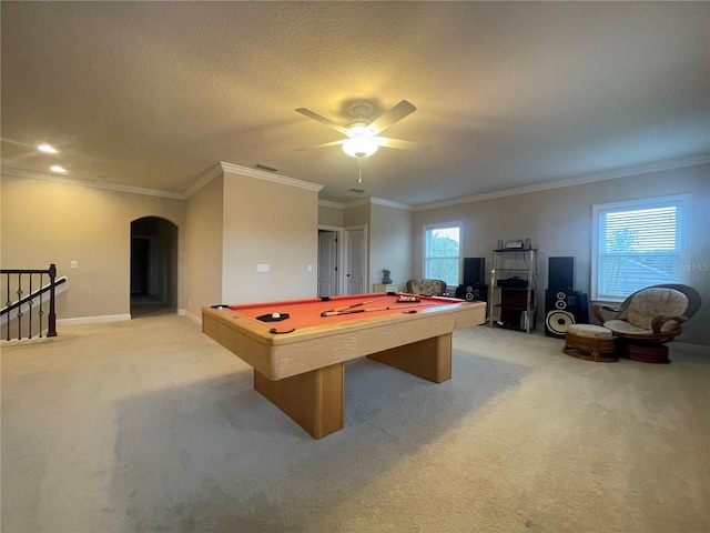 playroom featuring light carpet, a textured ceiling, arched walkways, and crown molding