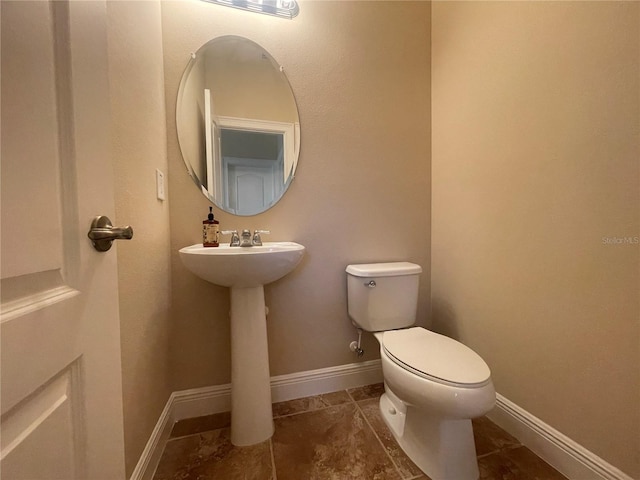 half bathroom featuring toilet and baseboards