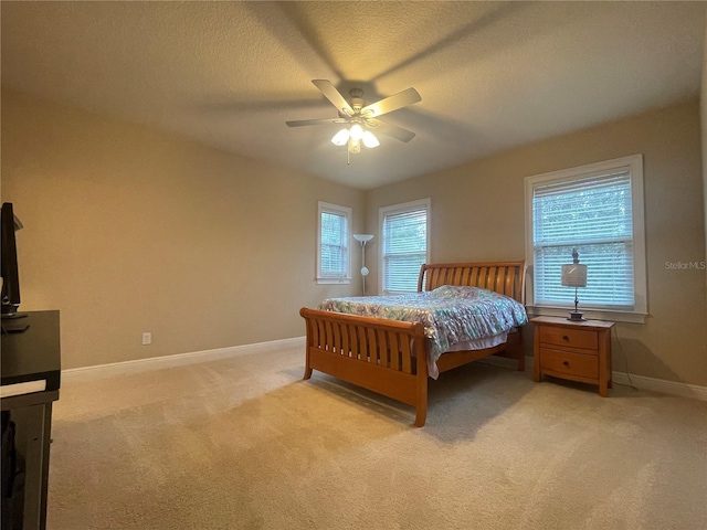 bedroom featuring baseboards, ceiling fan, a textured ceiling, and light colored carpet