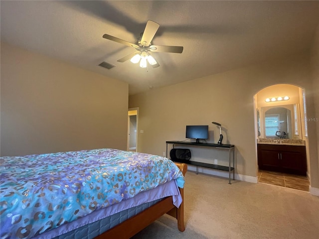 bedroom with light carpet, baseboards, visible vents, a ceiling fan, and ensuite bathroom